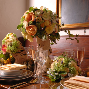 Tree peonies in apricot with Viburnum and Clematis all arranged in tree trunks.  Rustic and romantic.